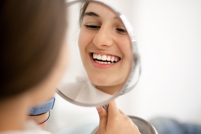 a girl checking her teeth in mirror